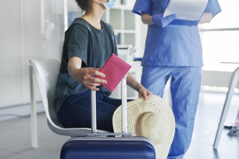 Close up woman holding passport and luggage during travel vaccination