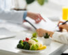 Dietitian reviewing a nutrition plan with a patient, with a plate of fresh vegetables and fruit on the desk